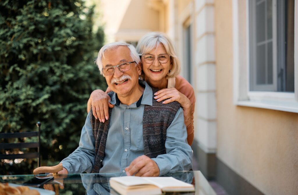 an older man and an older woman are both smiling and enjoying the senior care community they are part of.