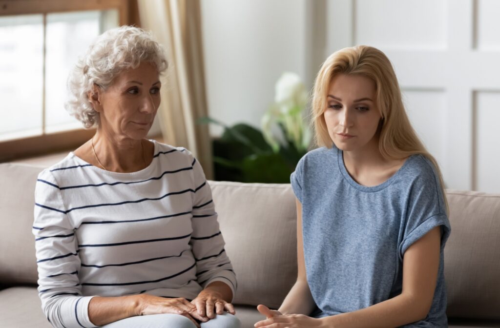 A senior looks with concern at their adult child, who is starting to withdraw after committing to full-time caregiving