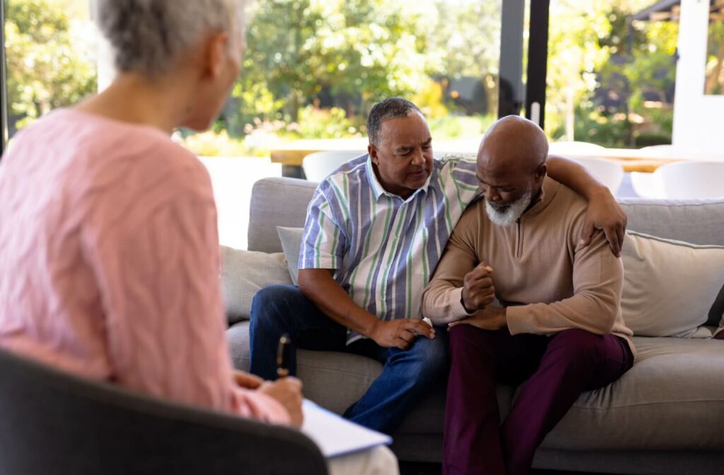 A senior leans on a supportive family member to talk to a therapist about options to support their family caring for them