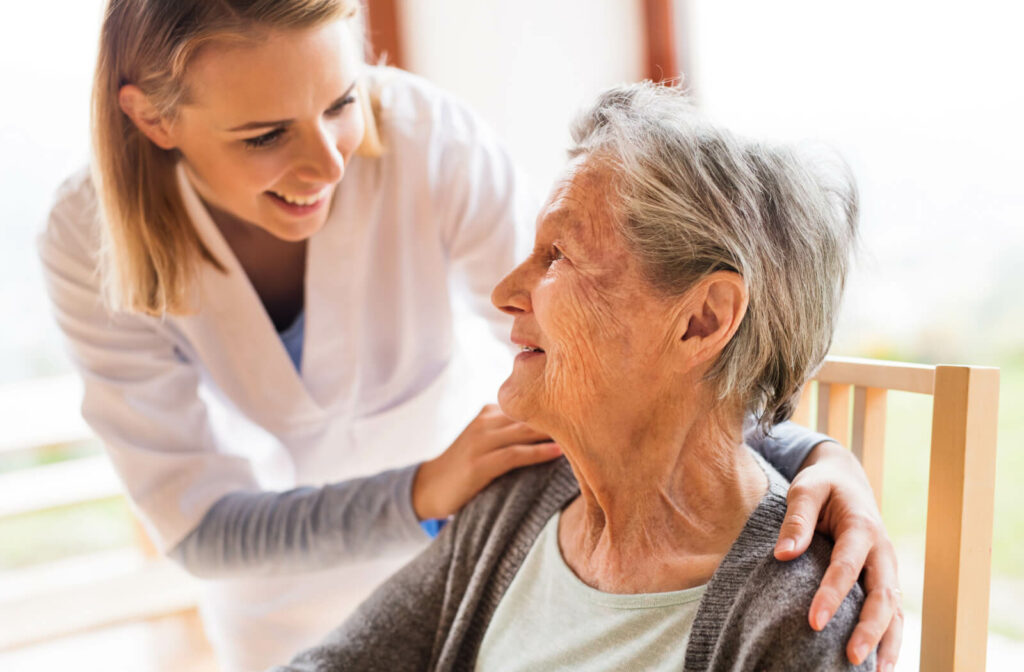 A smiling caregiver checking on an appreciative resident on a porch in assisted living.